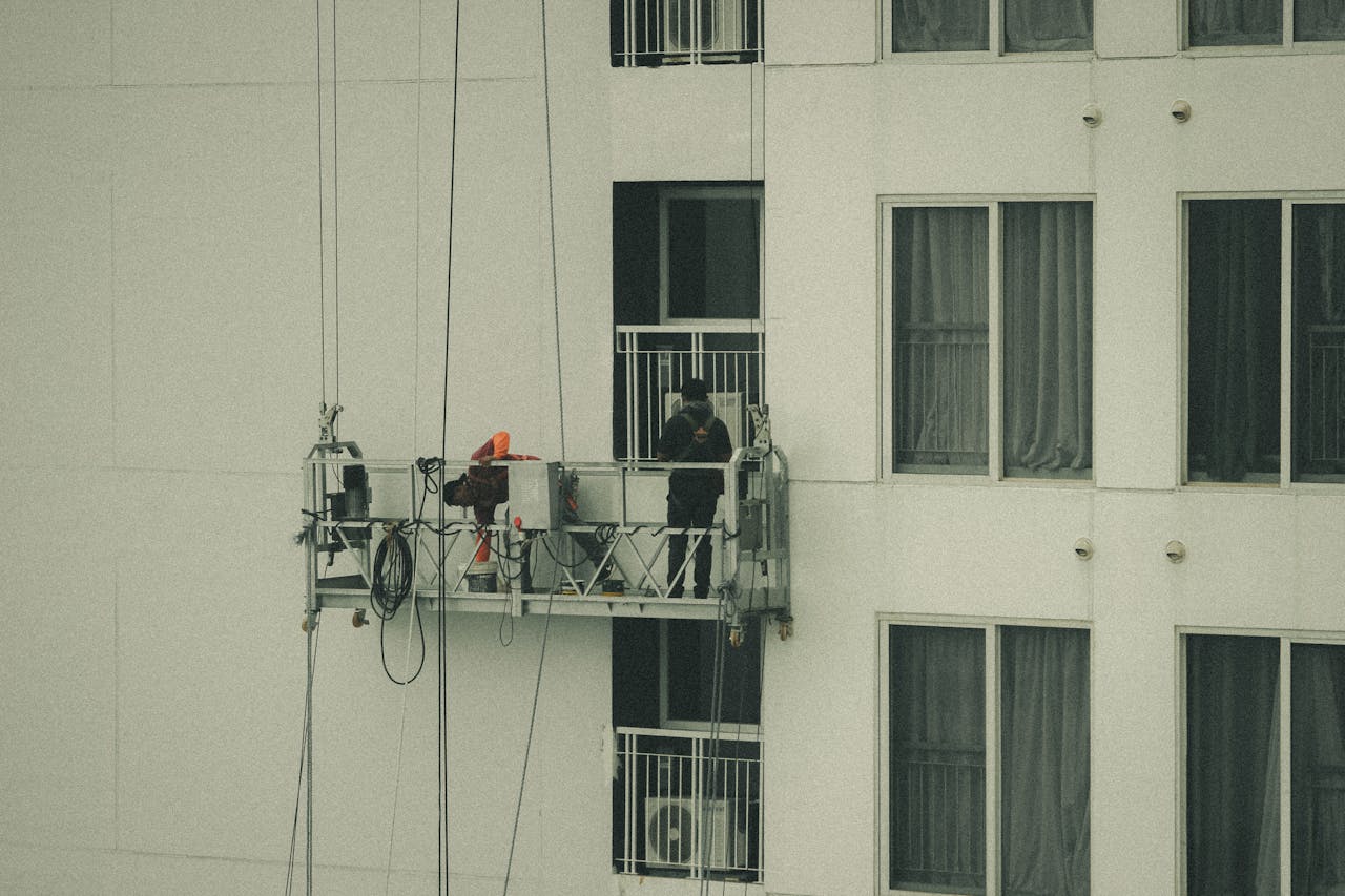 Workers on a suspended platform maintain a building facade in Tagaytay, Philippines.